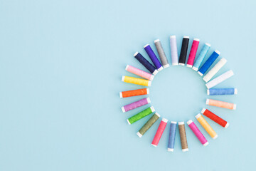 Panoramic detailed view of multi colored spools of thread on a blue background.