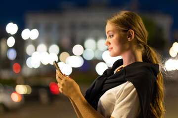 Young woman using smartphone in city at night