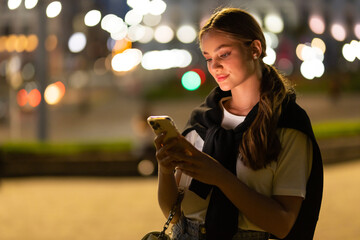 Young pretty woman texting cell phone in city at night