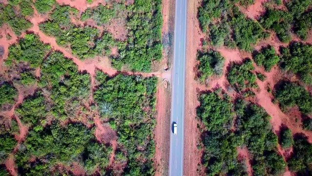 A Utility Vehicle With Tourists Driving On A Long Paved Road In The Countryside In Kenya, East Africa. - Drone Shot Vertical