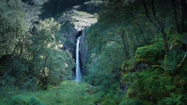 A view of the waterfall falling into a deep gorge. Tilt-shift video. Pan right.