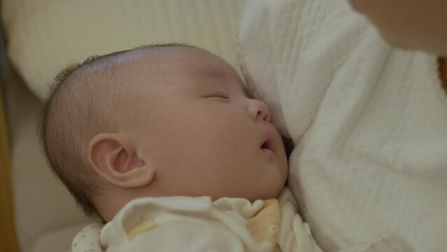The face of a baby sleeping in the mother's arms. Asian baby.