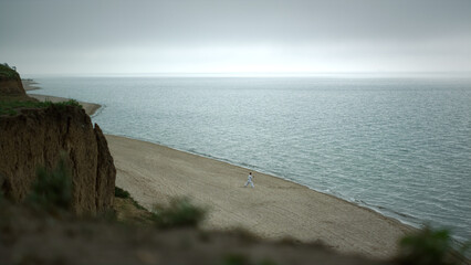 Tranquil scenery sandy beach cloudy morning. High hill standing on seacoast.