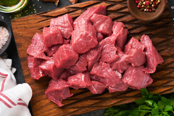 Raw chopped beef meat. Raw organic meat beef or lamb, spices, herbs on old wooden board on dark...