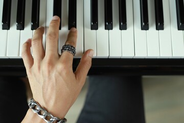 A rocker man plays the piano in the music room at school. favorite classical music Show your fingers on the piano keyboard.