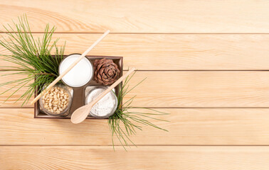 Cedar milk, flour, nuts, cone, branches in wooden box on wooden table. Banner. Top view. Copy space.