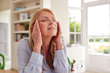 Menopausal Mature Woman At Home Suffering With Headache Pain