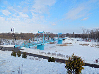 A blue bridge connecting the banks of a frozen river.