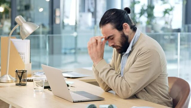 Angry young business man, feeling stress and the pressure of deadlines. Male web developer making a mistake while coding and banging his desk in frustration. Modern worker suffering from a headache