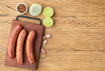 Calabrese pork sausage over wooden board with seasonings and copy space