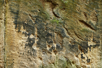The texture of an old stone on the defensive wall of a castle in the north of England. Old stone covered with dark green moss of different shades.