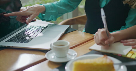 Senior executive female leader coaching younger employee in front of laptop. Closeup hand pointing...