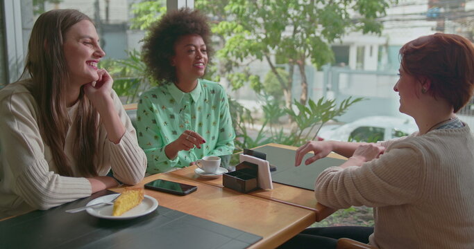 Happy Diverse Female Friends Hanging Out Together At Coffee Shop. Three Young Women Talking Inside Cafe Smiling And Laughing