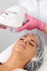 LED light anti-aging mask for facial skin care in a spa slow motion. A woman lies on a couch in a...