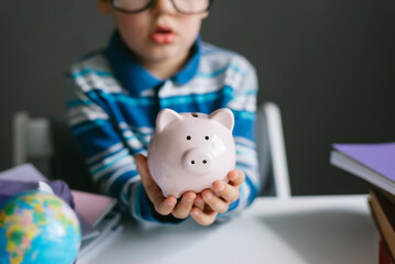 One toddler boy 3 years old collects coins in a piggy bank. Paid education, children's money concept.