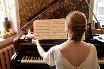 girl in a long white dress sits next to the piano