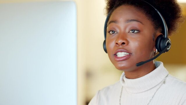 Black call center agent wearing a headset and working in a modern office. Young African American woman talking on a video conference. Female focused while explaining and working in customer care