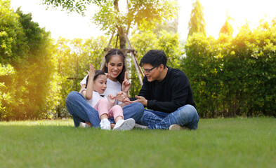 Fototapeta premium Asian family A cute and bright daughter is resting by running in the field.