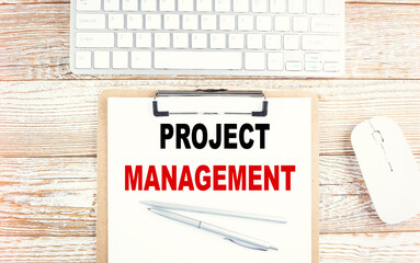 PROJECT MANAGEMENT text on clipboard with keyboard on wooden background