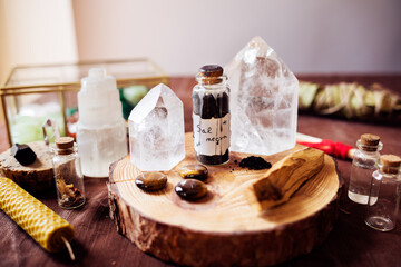 Witch altar for protection rituals against bad energies. There is a glass jar with black salt and three tiger's eye stones, palo santo and several quartz stones for energy cleaning. 