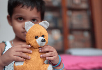 Portrait of an adorable little Indian girl obscuring her face while playing with a doll. Selective focus on face of the doll.