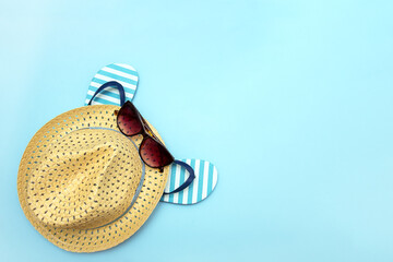 beach accessories - straw hat, sunglasses, flip flops on a blue background, linen background, copy space