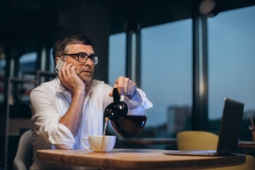 Tired businessman spills coffee on the table..
