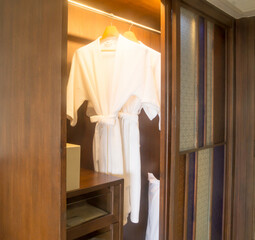 Two elegant white bathing gowns hanging in wardrobe in hotel nicely prepared to serve for guests - obrazy, fototapety, plakaty