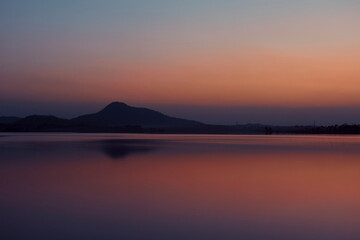 Fototapeta na wymiar Dramatic hued skyline of Barhanti (Baranti) Hill and adjoining Baranti lake just after sunset. The lake is a man-made water reservoir. It is a popular travel destination in Purulia district of Bengal.
