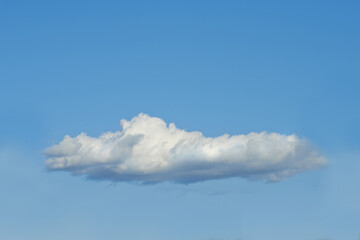 Copy space with a cloud isolated against a clear blue sky on a sunny day outside. One single fluffy and white cloud floating in a peaceful landscape wallpaper and quiet scene for nature background