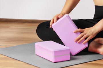 Woman yoga workout with yoga blocks on yoga mat indoor. Healthy lifestyle.