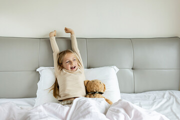 Candid lifestyle portrait of Cheerful caucasian child eight years old in pajamas having fun on bed...