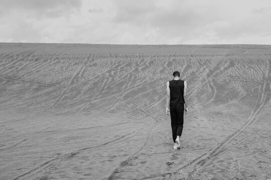 Young man walking alone on the sand in sandy desert