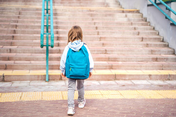 Back to elementary, primary school. Little girl with big backpack goes in hurry, late to first...