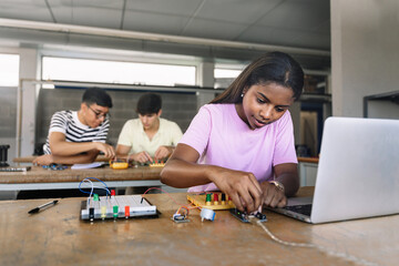 African American High School teenage Student programming electronics circuit board in the science...