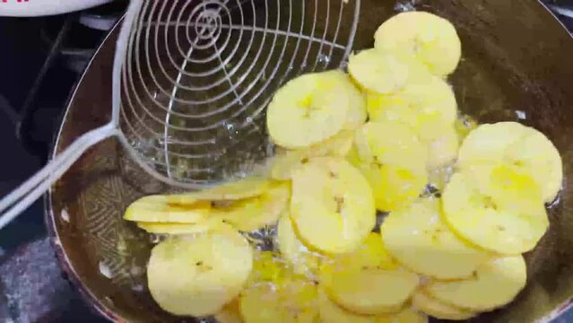 Woman frying green banana in hot oil 4K Man cooking on the stove. Fried patacones. preparing fried green banana. close up kitchen.