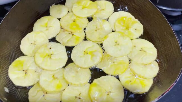 Woman frying green banana in hot oil 4K Man cooking on the stove. Fried patacones. preparing fried green banana. close up kitchen.