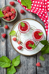 Fototapeta premium Healthy breakfast. Glass jars with chia pudding with raspberry and jam or smoothies with chia seeds on rustic table. View from above.