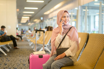 Fototapeta premium Young female muslim traveler carrying suitcases at the International airport, travel, holidays and journey concept..