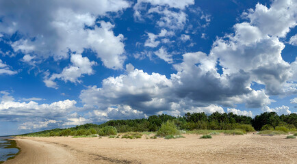 Fototapeta na wymiar Panorama of the warm Gulf of Riga of the Baltic Sea against the background of cumulus clouds. The coast of the Gulf of Riga in Latvia is popular with tourists.