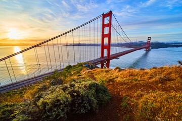 View from trail on cliffs of iconic Golden Gate Bridge at sunrise