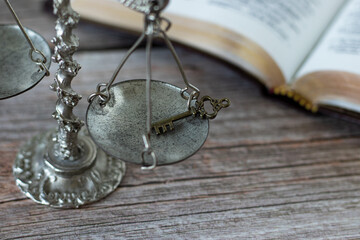 Antique weighing balance scale, an old key, and an open Holy Bible Book with golden pages on a...