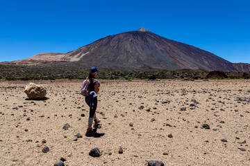 Woman on La Canada de los Guancheros dry desert plain with view on volcano Pico del Teide, Mount El Teide National Park, Tenerife, Canary Islands, Spain, Europe. Hiking to Riscos de la Fortaleza