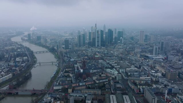 Fly above metropolis. Group of downtown skyscrapers towering above town development. Bridge spanning wide river. Frankfurt am Main, Germany