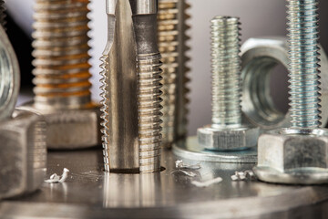 Thread tap drill steel billet with drill bit on background. Working cutter.