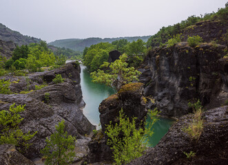A picturesque and tranquil place with a calm river in a rocky gorge during a colorful summer. Rainy summer in a nature park