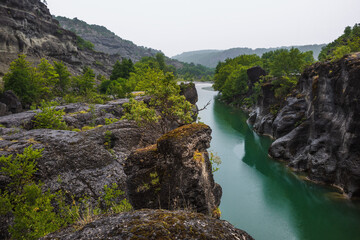 A picturesque and tranquil place with a calm river in a rocky gorge during a colorful summer. Rainy summer in a nature park