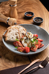 Salad with burrata and ripe tomatoes, garnished with microgreens and balsamic dressing and crispy ciabatta