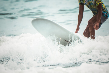 Blurred soft images of people are playing surffboard in the sea, a sport that requires strength and...