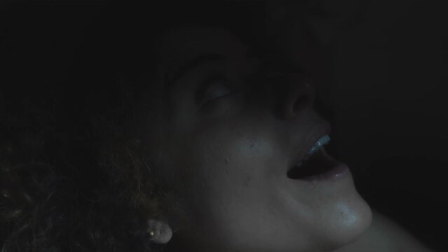 young psychotic woman with a crazy gaze smiling under a flashing light 